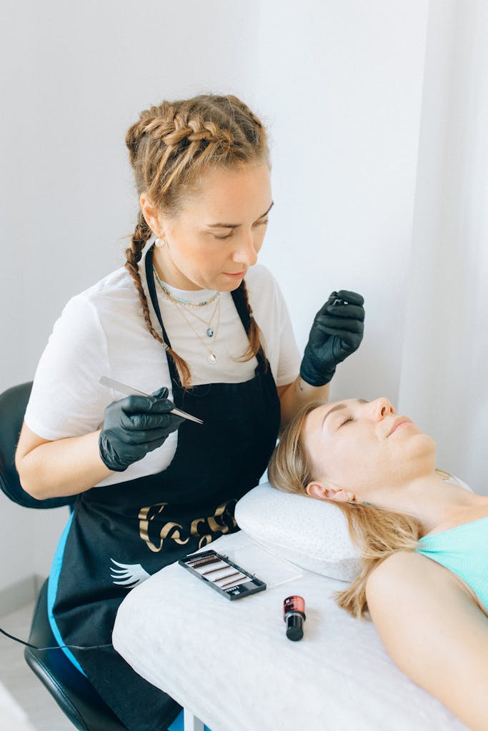 Woman in White and Apron Sitting Near a Woman Lying Down